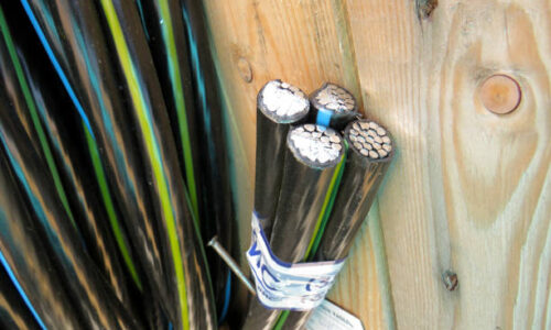 Electric power copper cable in black insulation on a wooden coil for laying electrical networks, concept of electrical installation works and services, electrical products