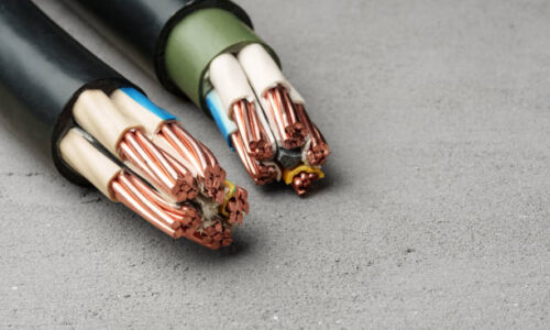 istockphoto-2160387117-612x612 A close-up image of various types of electrical wires arranged horizontally on a gray concrete surface.